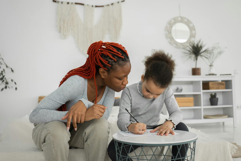 Black woman and girl doing task at table